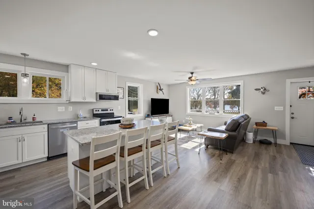 a living room with stainless steel appliances furniture and a wooden floor