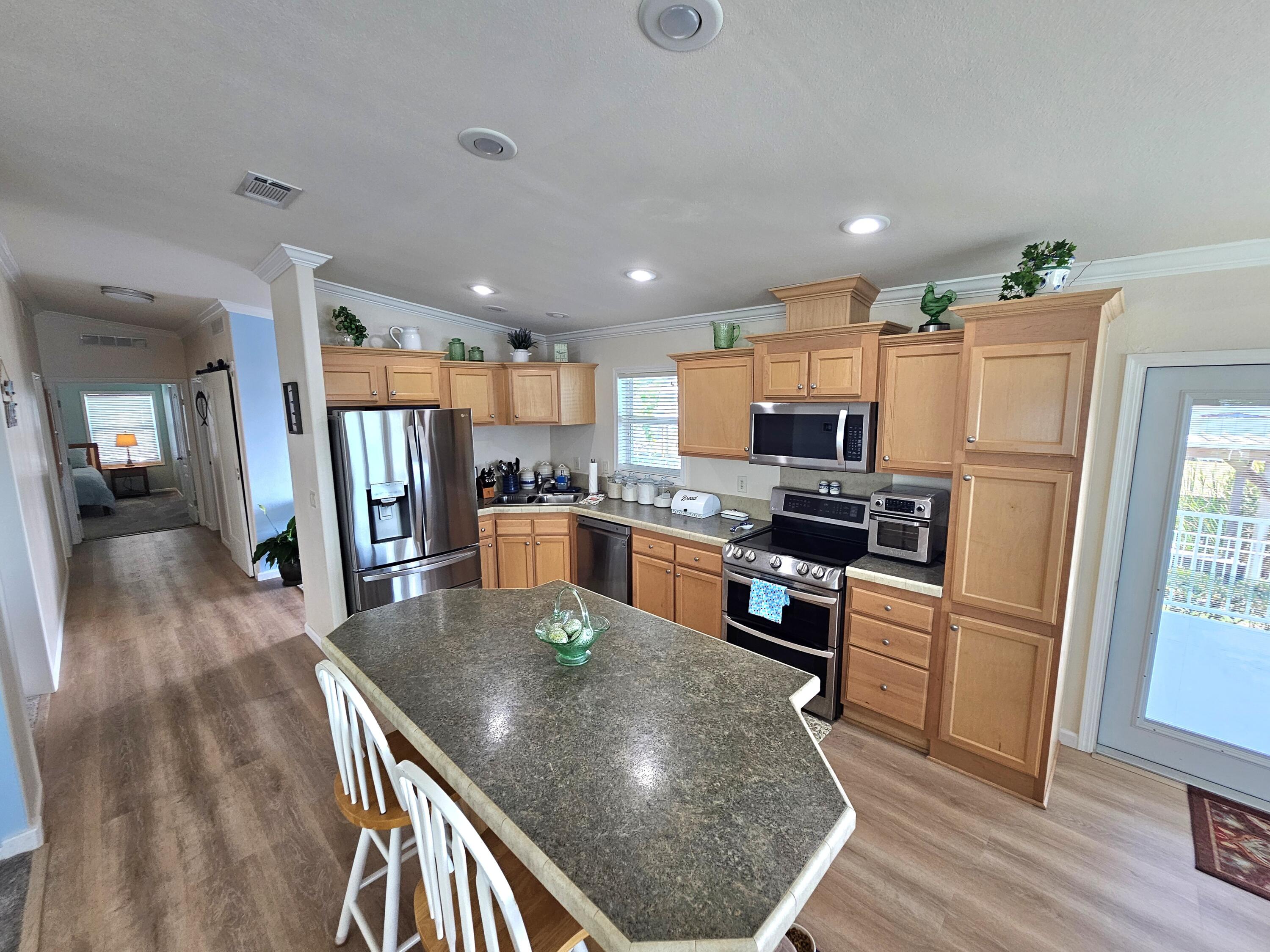 7902 Southeast 95th Trail Okeechobee, FL 34974 - Photo 11 of 36 a kitchen with stainless steel appliances granite countertop a refrigerator a stove top oven a sink dishwasher and white cabinets with wooden floor