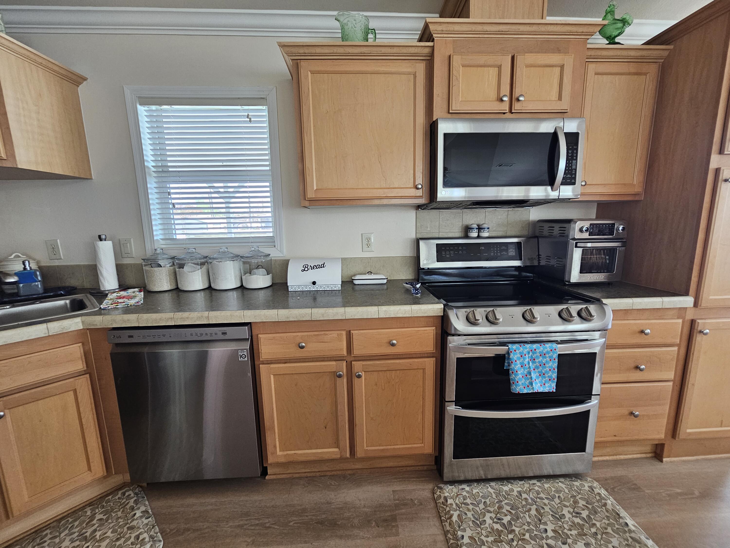 7902 Southeast 95th Trail Okeechobee, FL 34974 - Photo 13 of 36 a kitchen with stainless steel appliances a stove a sink a microwave and cabinets