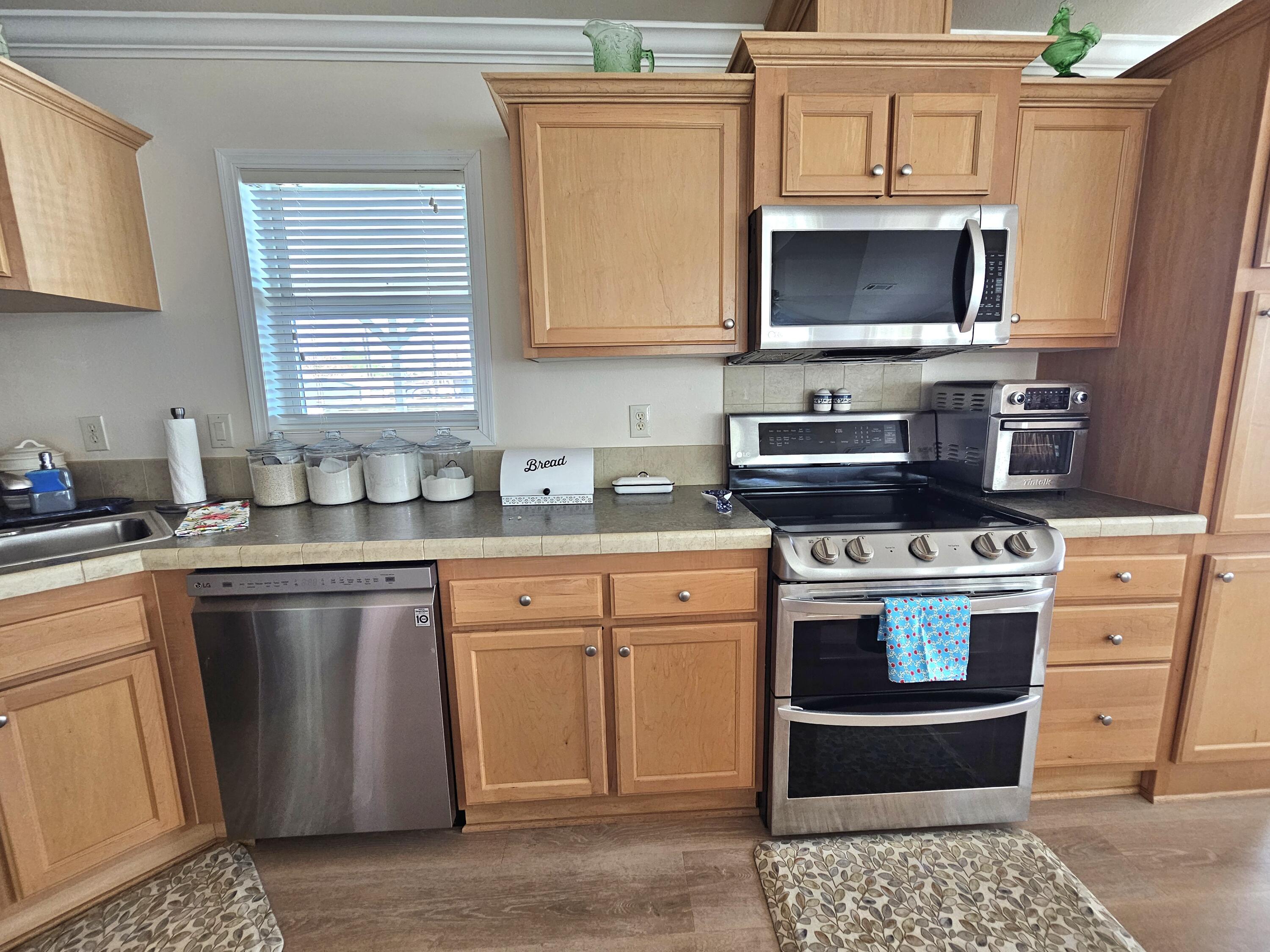 7902 Southeast 95th Trail Okeechobee, FL 34974 - Photo 14 of 36 a kitchen with stainless steel appliances granite countertop a stove a sink and a microwave