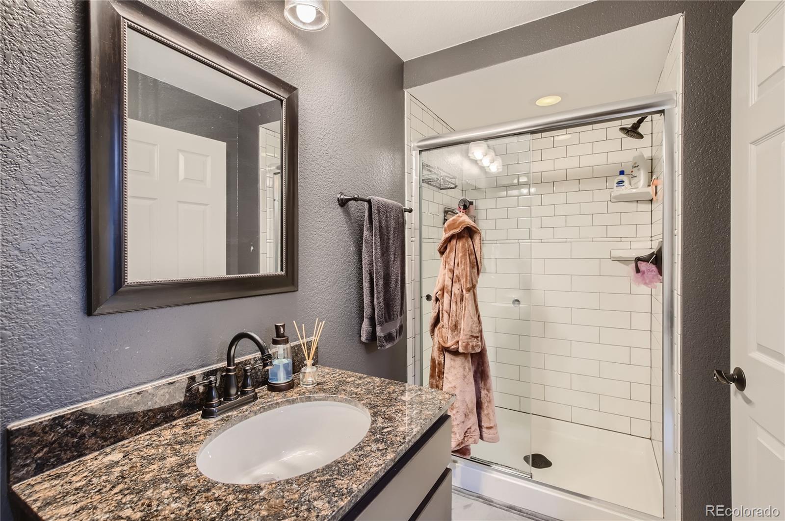 8481 West 95th Drive Westminster, CO 80021 - Photo 18 of 28 a bathroom with a granite countertop shower a mirror and vanity