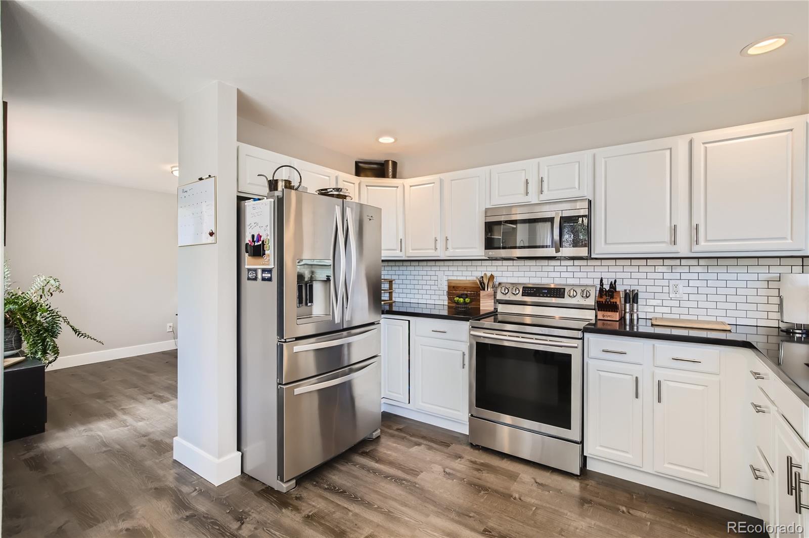 8481 West 95th Drive Westminster, CO 80021 - Photo 3 of 28 a kitchen with white cabinets and stainless steel appliances