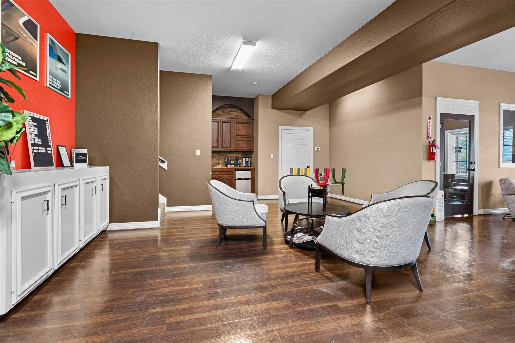 11066 Sh 242 Conroe, TX 77385 - Photo 9 of 21 This inviting room features warm wood flooring and neutral walls with a bold red accent. It includes comfortable seating, a small kitchenette area, and ample storage. An ideal space for relaxation or informal meetings.