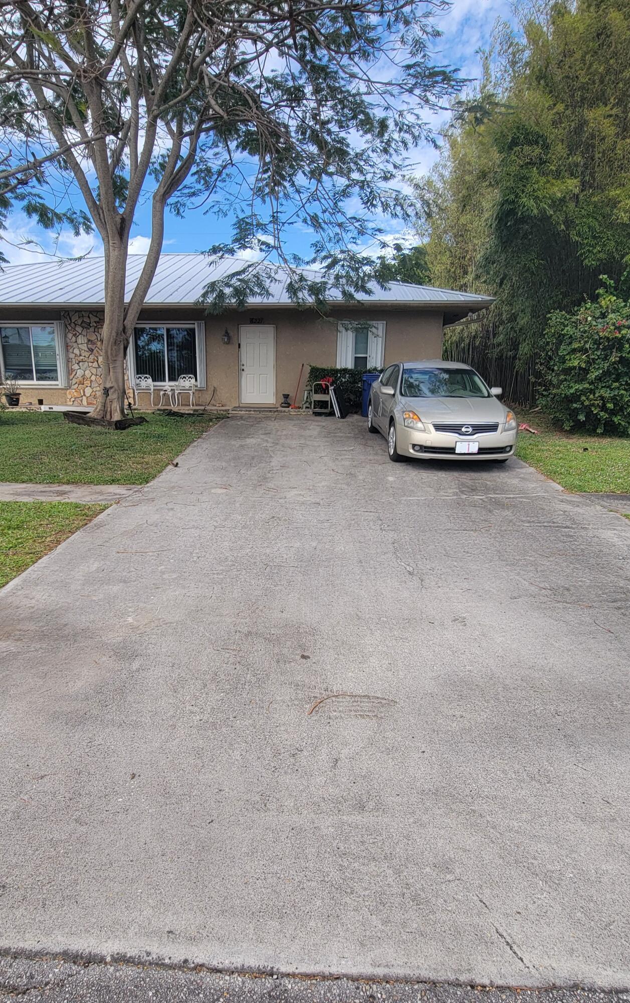 6221 Allen Street Jupiter, FL 33458 - Photo 2 of 2 a car parked in front of house with a yard