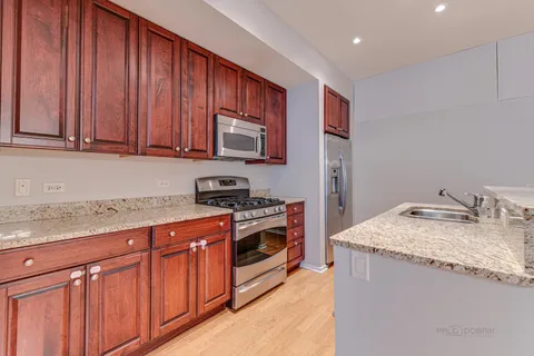 a kitchen with granite countertop stainless steel appliances a stove sink and cabinets