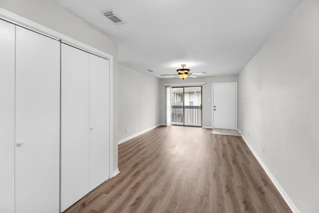 an empty room with wooden floor and windows