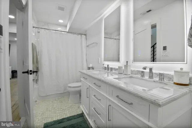 a bathroom with a granite countertop sink a toilet and a shower