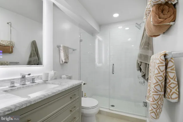 a bathroom with a granite countertop sink a toilet and shower