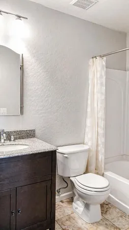 a bathroom with a granite countertop toilet sink and mirror