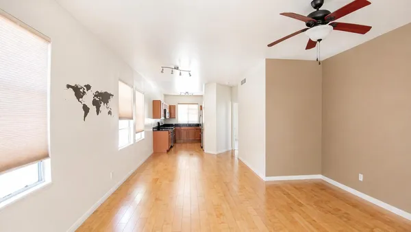 a view of kitchen with an empty room and wooden floor