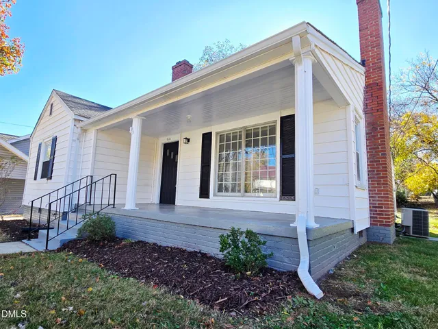 a view of a house with brick walls and a yard with plants