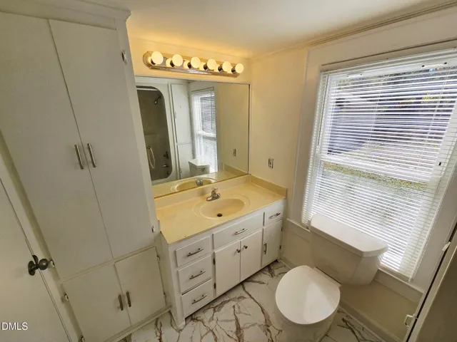 a bathroom with a granite countertop toilet sink and mirror
