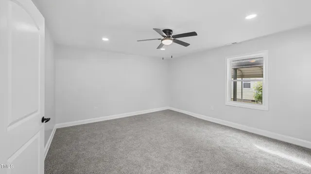 an empty room with a window and ceiling fan
