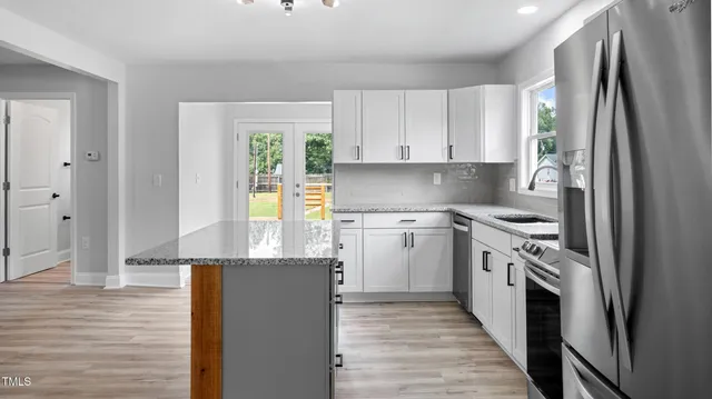 a kitchen with stainless steel appliances granite countertop a refrigerator a stove and a sink