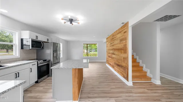 a kitchen with stainless steel appliances granite countertop a refrigerator a stove a sink and a wooden floors