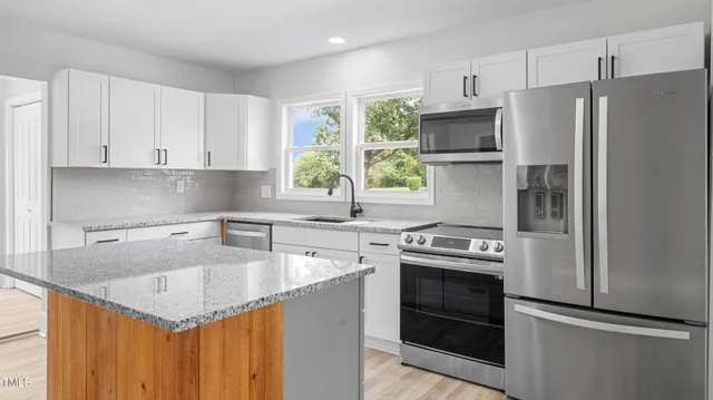 a kitchen with stainless steel appliances granite countertop a sink stove and refrigerator