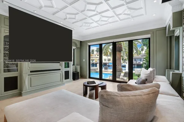 a living room with furniture a flat screen tv and floor to ceiling window