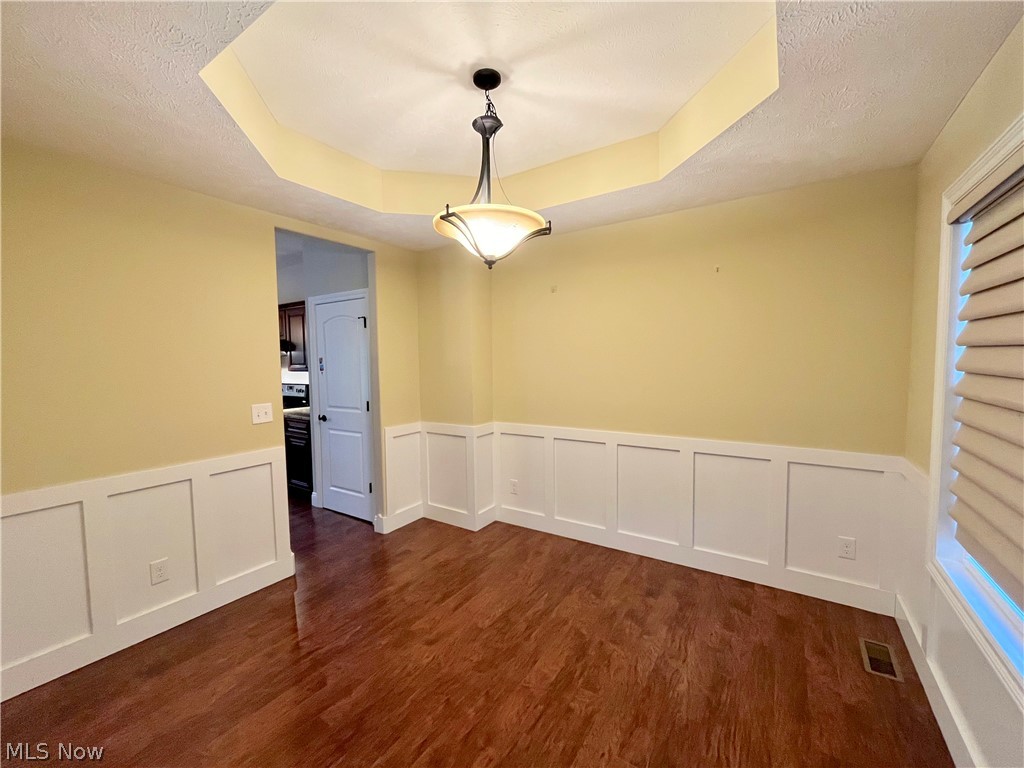 1134 Mayfield Ridge Road Cleveland, OH 44124 - Photo 6 of 41 Spare room with a textured ceiling, dark wood-type flooring, and a raised ceiling