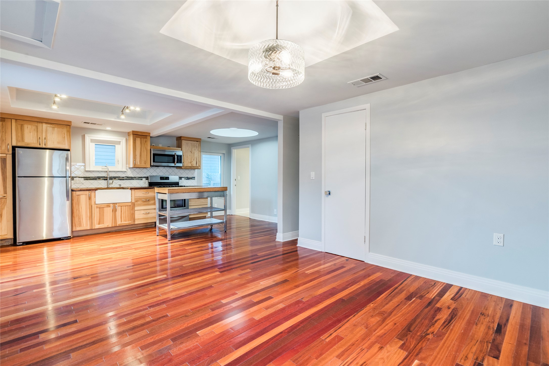 2314 Santa Rosa Street Austin, TX 78702 - Photo 10 of 29 Hardwood floors stretch across this open-concept space, leading to a well-appointed kitchen featuring natural wood cabinetry and stainless steel appliances.
