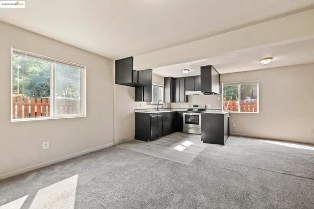 a kitchen with stainless steel appliances a refrigerator a sink a stove top oven a counter space and cabinets