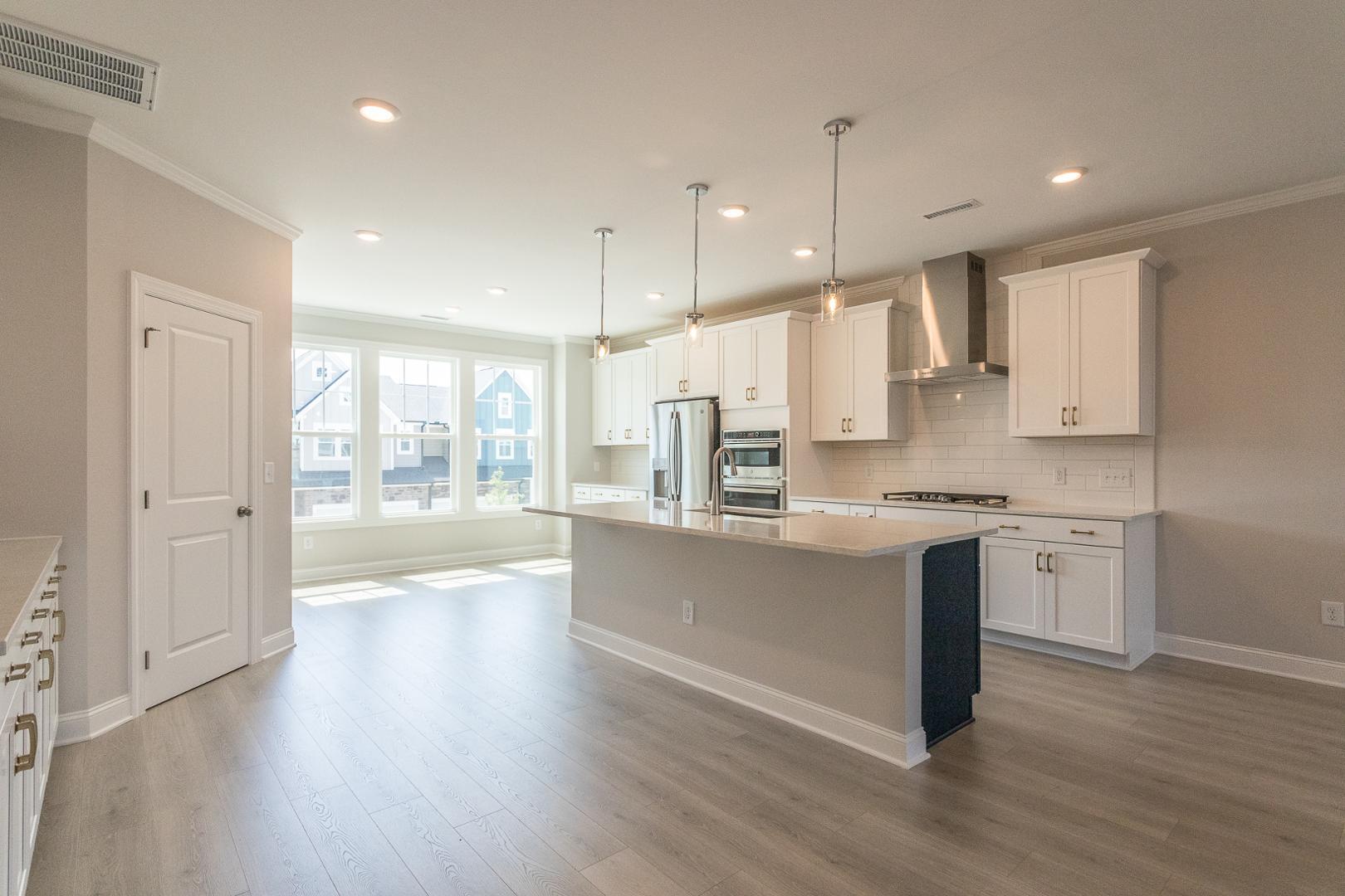 8421 Zinc Autumn Path Raleigh, NC 27615 - Photo 30 of 33 a kitchen with stainless steel appliances granite countertop a sink a stove a refrigerator and white cabinets with wooden floor