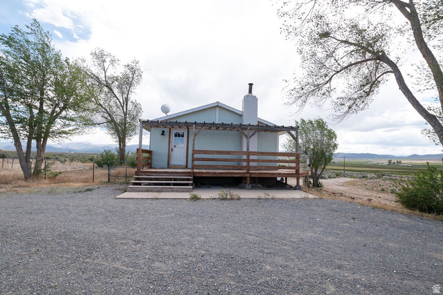 570 West Main Street Beaver, UT 84713 - Photo 5 of 43 Light blue siding exterior with a white entry door, an expansive wood deck, and a prominent chimney feature