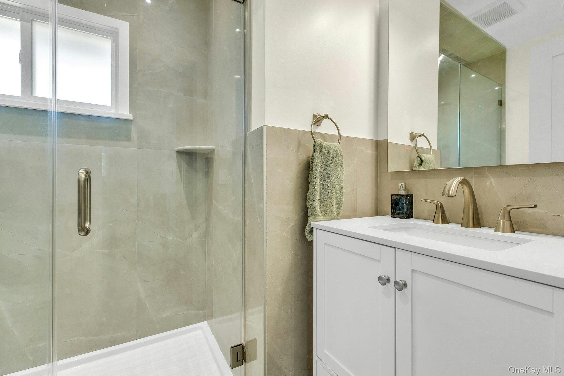20 Robert Road Glen Cove, NY 11542 - Photo 15 of 24 a bathroom with a sink a mirror and shower