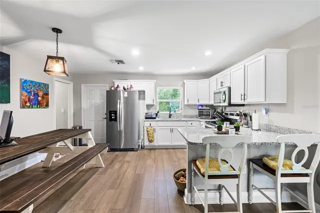 a kitchen with stainless steel appliances granite countertop a refrigerator a sink dishwasher a stove and white countertops with wooden floor