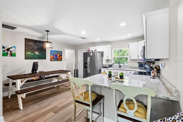 a kitchen with stainless steel appliances granite countertop a stove a sink dishwasher and white cabinets with wooden floor