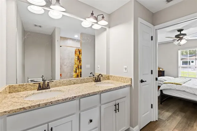 a en suite bathroom with a granite countertop double vanity sink and a mirror