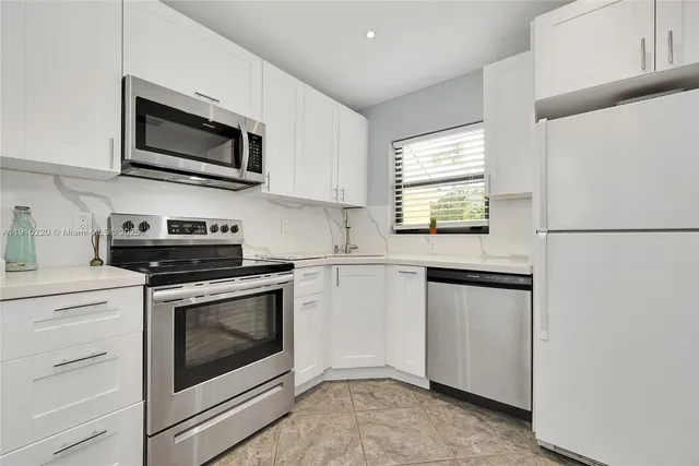 a kitchen with white cabinets stainless steel appliances and sink
