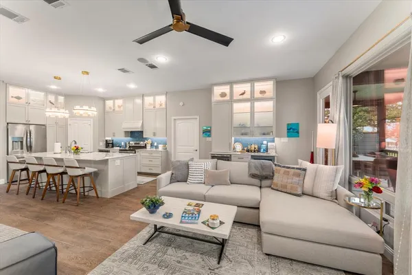 a living room with furniture kitchen view and a large window