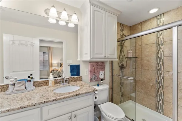 a bathroom with a granite countertop sink a toilet and shower