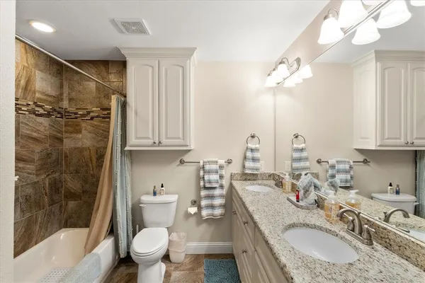 a bathroom with a granite countertop sink a toilet a mirror and shower