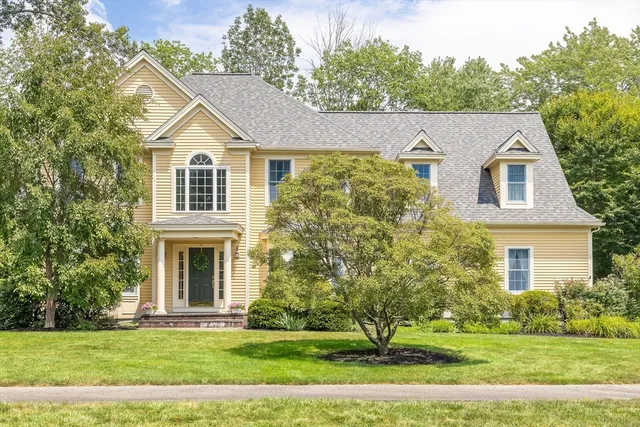 a view of a white house next to a yard with big trees