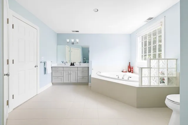 a bathroom with a bathtub sink mirror vanity and toilet