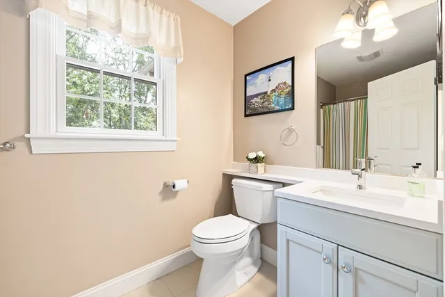 a bathroom with a toilet a sink a mirror and a window