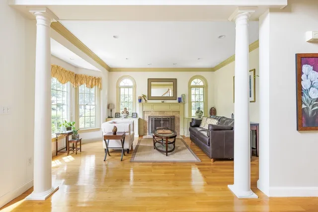 a living room with fireplace furniture large window and wooden floor