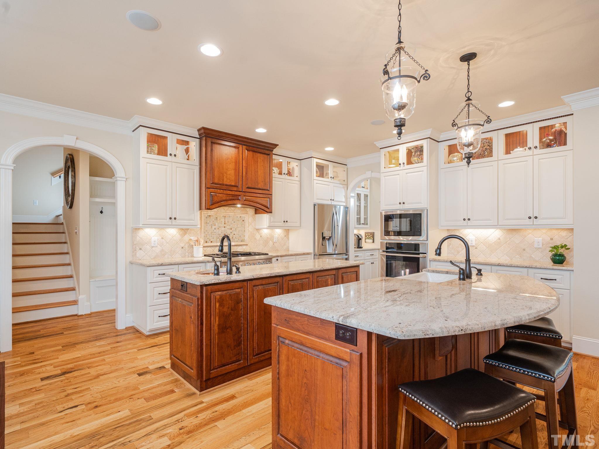 842 Cranbrook Road Raleigh, NC 27609 - Photo 10 of 39 a kitchen with kitchen island a stove a sink a refrigerator and chairs