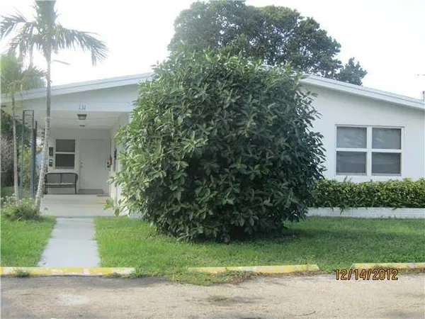 a front view of a house with a garden and yard