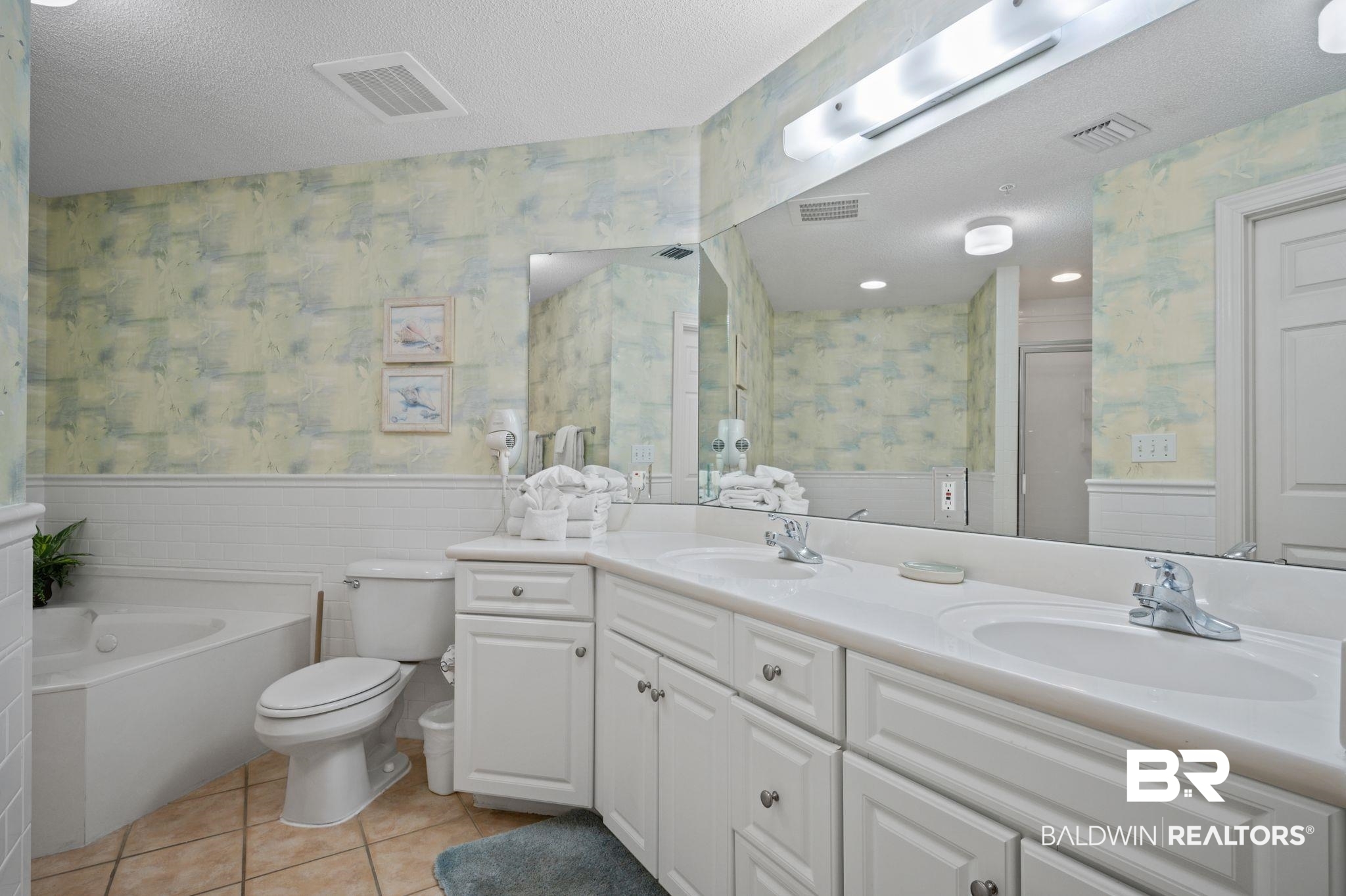 27580 Canal Road, Unit 1427 Orange Beach, AL 36561 - Photo 23 of 38 Full bathroom with wallpapered walls, double vanity, a garden tub, a textured ceiling, and wainscoting