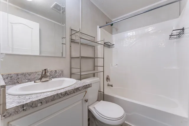 a bathroom with a granite countertop sink toilet and shower