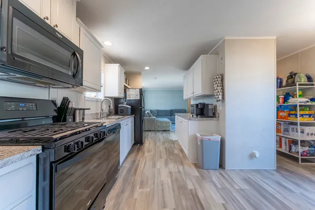 a kitchen with stainless steel appliances a stove a sink a refrigerator cabinets and a wooden floor