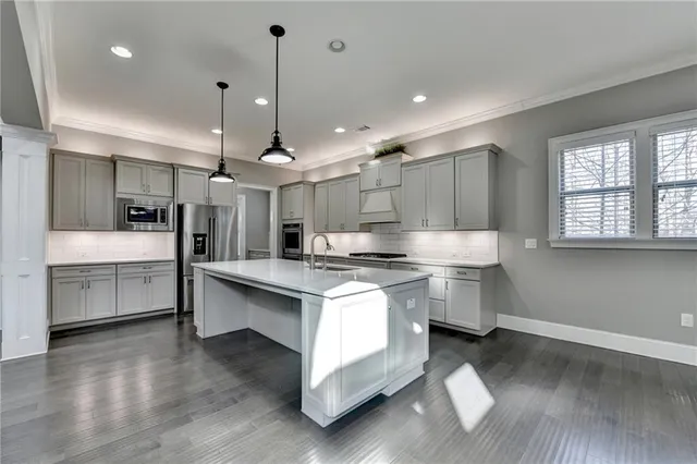 a kitchen that has a lot of white cabinets and stainless steel appliances