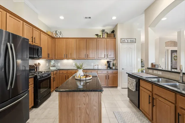 a kitchen with stainless steel appliances granite countertop a refrigerator a stove and a sink