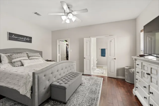a bedroom with a bed a mirror on dresser and wooden floor