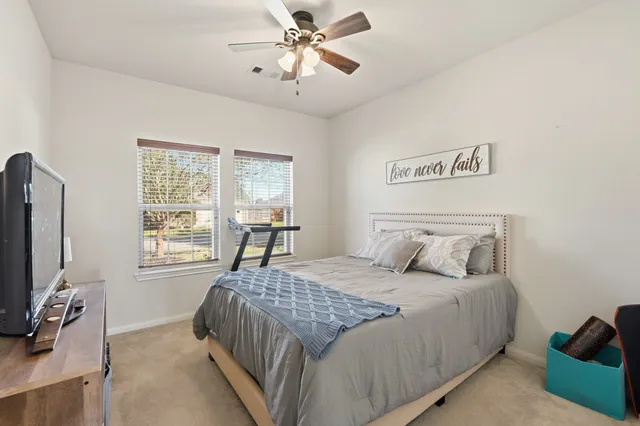 a bedroom with a bed a chandelier and a flat screen tv