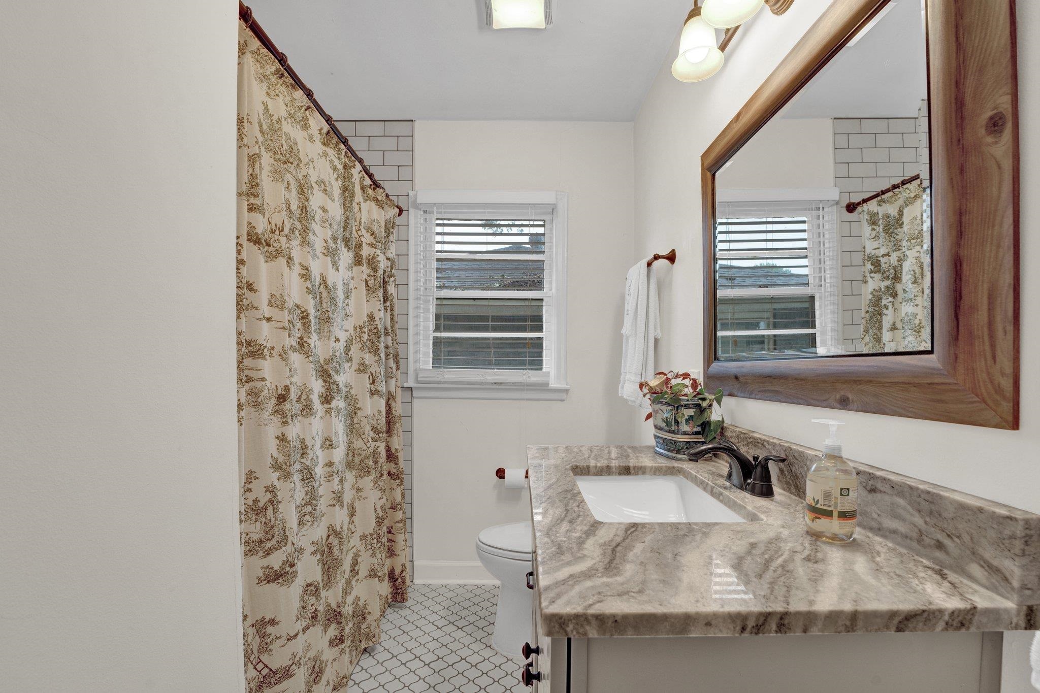 1459 Colonial Road Memphis, TN 38117 - Photo 23 of 33 a bathroom with a granite countertop sink a mirror and shower