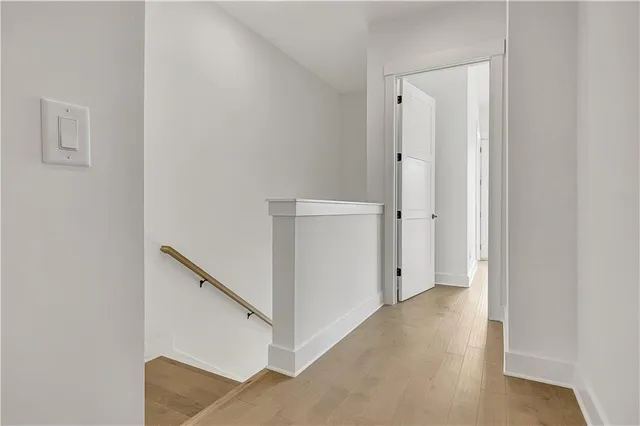 a view of an empty room with wooden floor and windows
