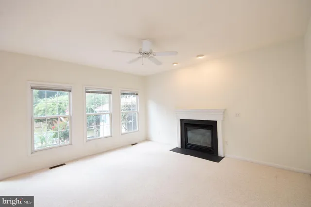 an empty room with windows and fireplace